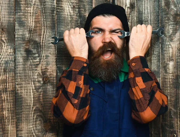 Bearded brutal caucasian mechanic holding metallic wrenches — Stock Photo, Image