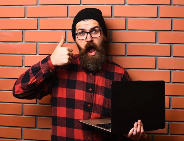 Bearded brutal caucasian hipster holding laptop — Stock Photo, Image