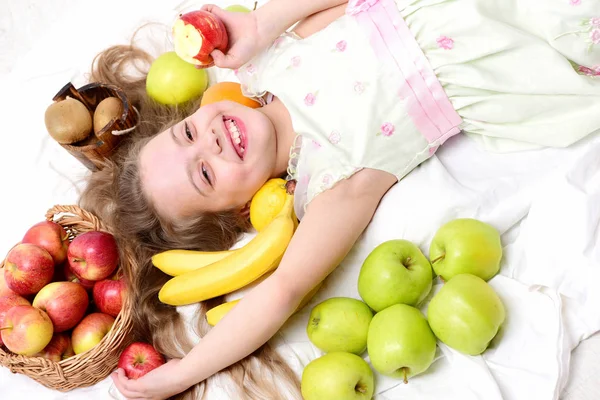 Niedliche Baby-Mädchen legen mit bunten Früchten im Korb — Stockfoto