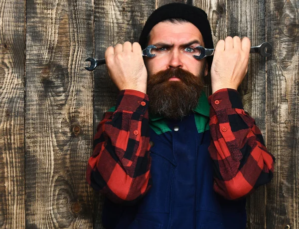 Bearded brutal caucasian mechanic holding metallic wrenches