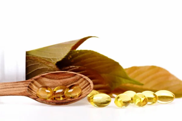 Fish oil omega 3 gel capsules in spoon with leaves — Stock Photo, Image