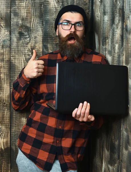 Bearded brutal caucasian hipster holding laptop — Stock Photo, Image