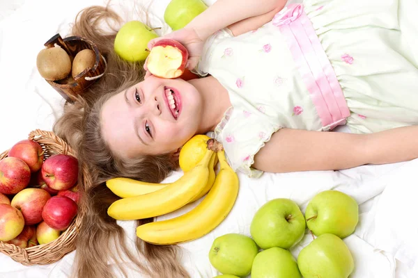 Kind, süßes Mädchen, das mit bunten Früchten im Korb liegt — Stockfoto