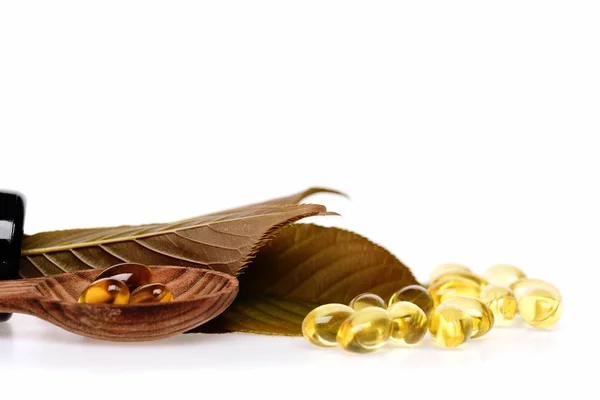 Fish oil omega 3 gel capsules in spoon with leaves — Stock Photo, Image