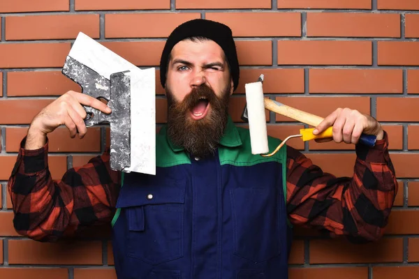 Бородатый мастер держит различные строительные инструменты с довольным лицом — стоковое фото