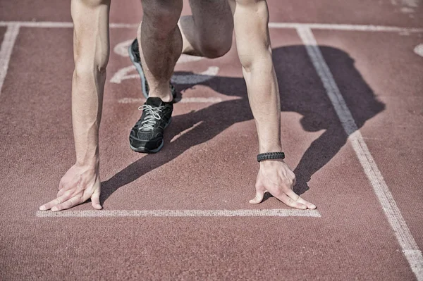 Hombre corredor con las manos musculosas, las piernas comienzan en pista de atletismo — Foto de Stock
