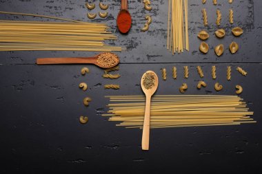 Makarna ve tahta kaşıklar gri yüzeyi koymak içinde baharatlar