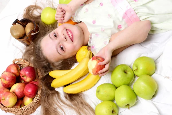 Kind, süßes Mädchen, das mit bunten Früchten im Korb liegt — Stockfoto