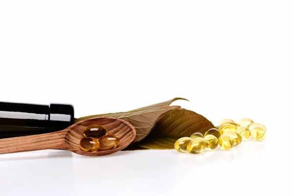 Dorsz oleju w kapsułki omega w drewnianą łyżką — Zdjęcie stockowe