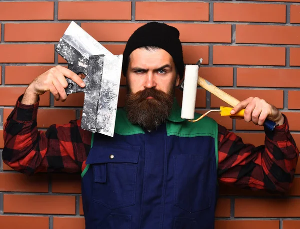 Bärtiger Malermann mit verschiedenen Bauwerkzeugen und ernstem Gesicht — Stockfoto