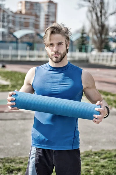 Homem muscular segurando ioga ou tapete de fitness para o exercício — Fotografia de Stock