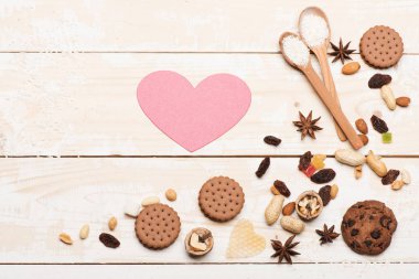 Tahta kaşıklar, fındık, bisküvi ve antika arka plan üzerinde pembe kalp