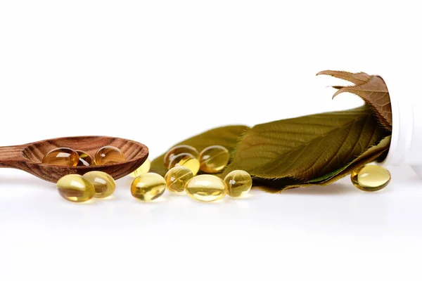 Fish oil omega 3 gel capsules in spoon with leaves — Stock Photo, Image