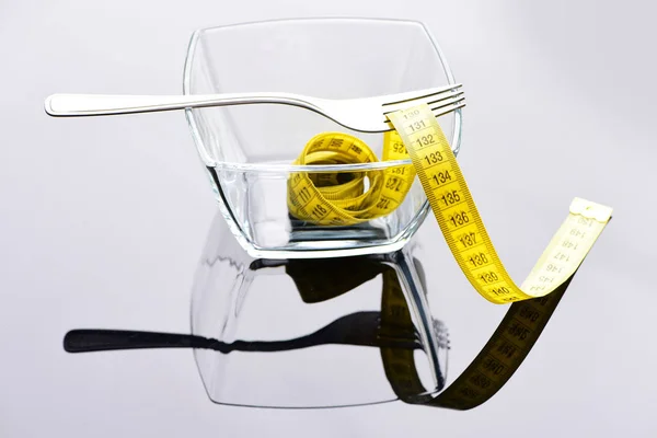 Cuenco de vidrio lleno de cinta métrica amarilla enrollada — Foto de Stock