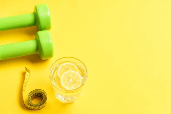 Concetto di fitness con manubri, metro a nastro e acqua al limone — Foto Stock