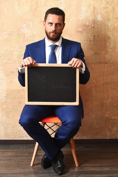 Hombre de negocios u hombre serio sosteniendo una pizarra — Foto de Stock