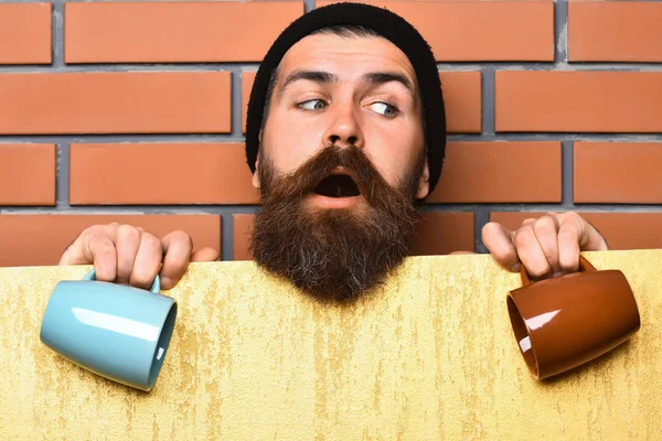 Barbudo brutal hipster caucásico con hoja de papel y tazas —  Fotos de Stock