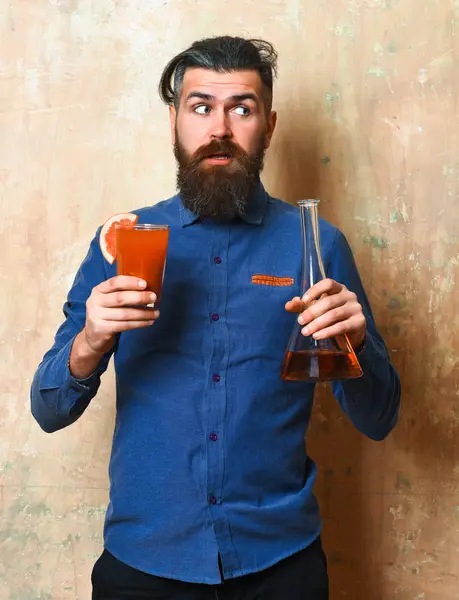 Brutalny hipster trzymający kieliszek i szklaną rurkę lub kolbę — Zdjęcie stockowe