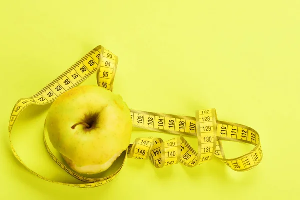 Envolvimento de maçã com fita métrica amarela — Fotografia de Stock