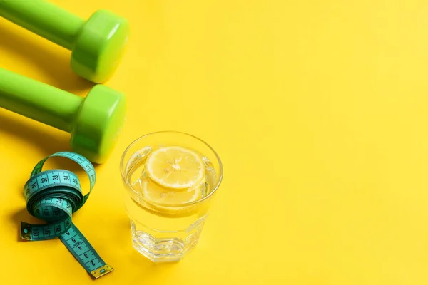 Sobrepeso con mancuernas, cinta métrica y agua con limón — Foto de Stock
