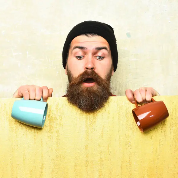 Barbudo brutal hipster caucásico con hoja de papel y tazas —  Fotos de Stock