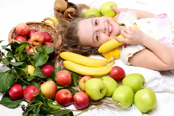 Niedliche Baby-Mädchen legen mit bunten Früchten im Korb — Stockfoto