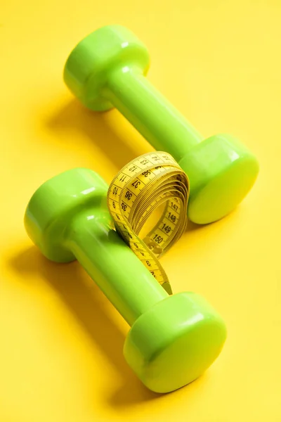 Halteres na cor verde com fita métrica no amarelo — Fotografia de Stock