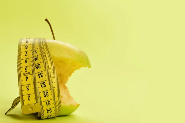 Apple bitten and wrapped by measuring tape