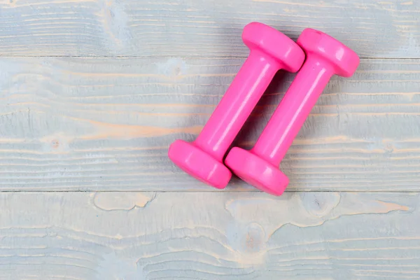 Conceito de ginásio esporte, halteres rosa em madeira vintage cinza — Fotografia de Stock