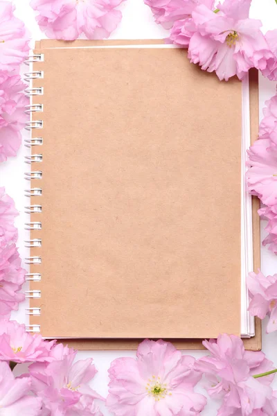 Bej rengi pembe sakura çiçeklerle çevrili içinde defter