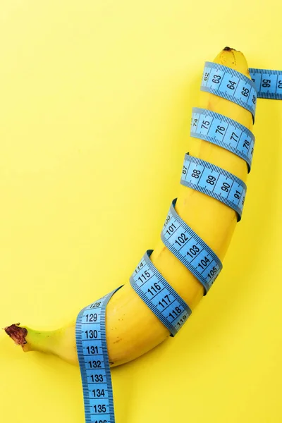 Nastro per la misurazione avvolto intorno alla banana sul giallo — Foto Stock