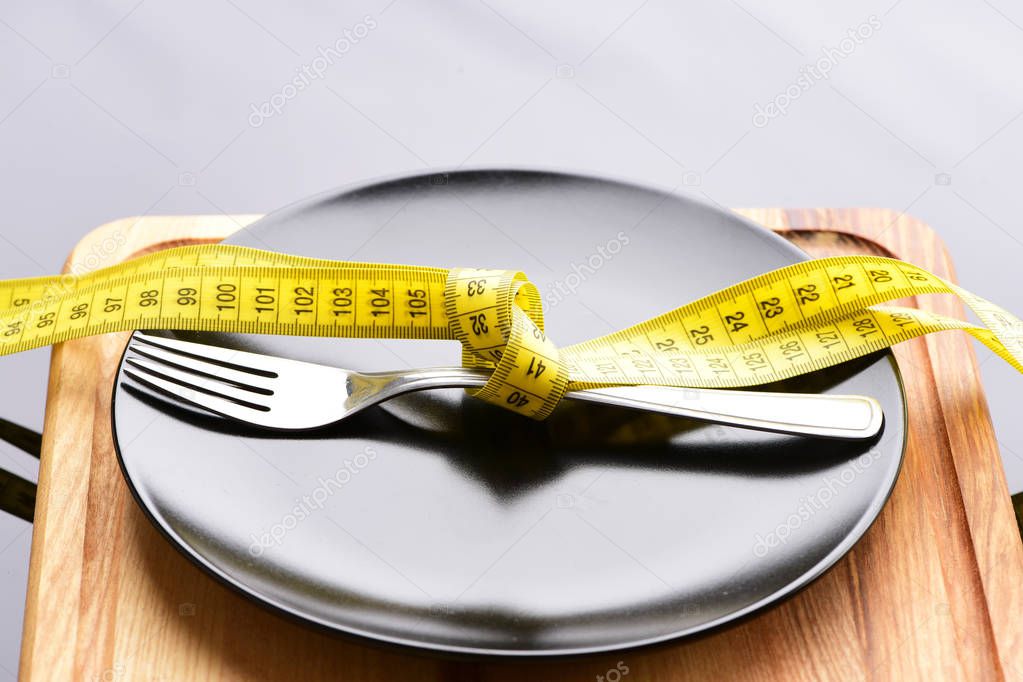 Fork tied with twisted yellow measuring tape lying on plate