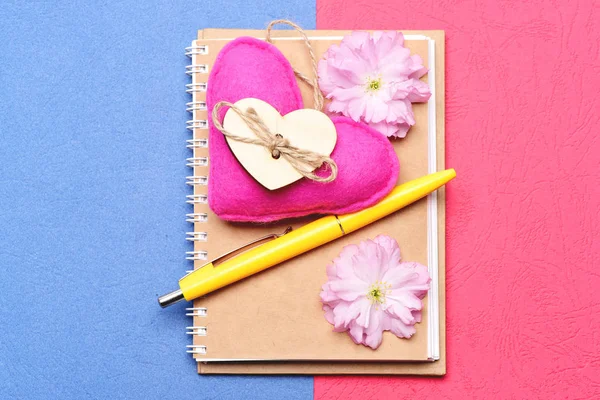 Notepad and pink handmade heart with blooming sakura flowers