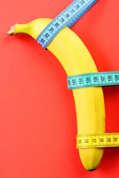 Banana tied around with colorful measuring tapes — Stock Photo, Image