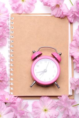 Çalar saat boş bej defter sayfası üzerinde pembe renkte