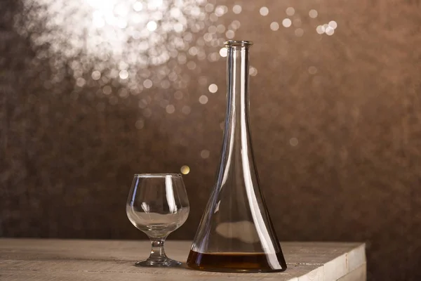 Garrafa de vidro perto de cone com bebida alcoólica na mesa de madeira — Fotografia de Stock