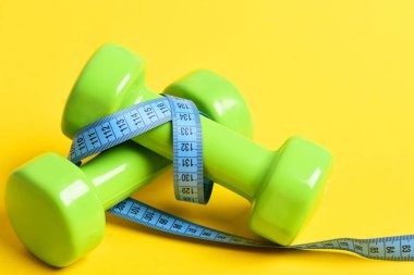 spor salonu ekipman konseptiyle dumbell ve ölçüm bandı