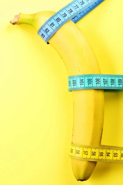 Pásky pro měření kravata kolem banán, izolované na žlutém podkladu — Stock fotografie