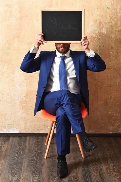 Hombre de negocios u hombre serio sosteniendo una pizarra — Foto de Stock