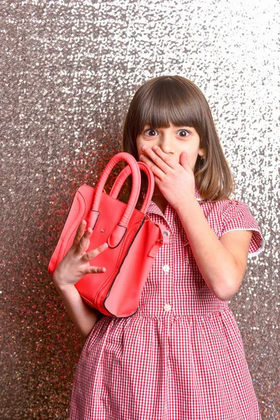 small pretty surprised girl with fashionable red leather bag