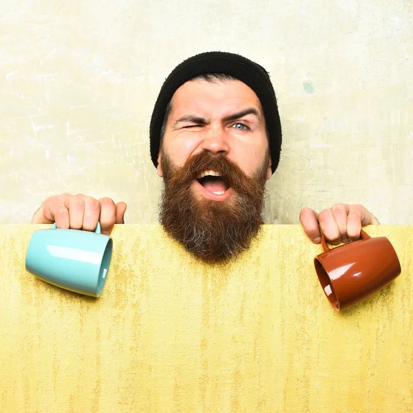 Barbudo brutal hipster caucásico con hoja de papel y tazas —  Fotos de Stock