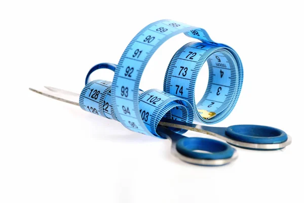 Riccioli di nastro di misurazione blu cinturati intorno alle forbici sartoriali — Foto Stock
