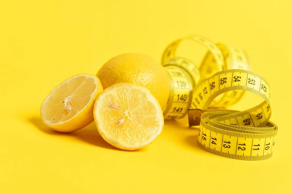 Pezzi di limone affettati con metro a nastro su fondo giallo — Foto Stock