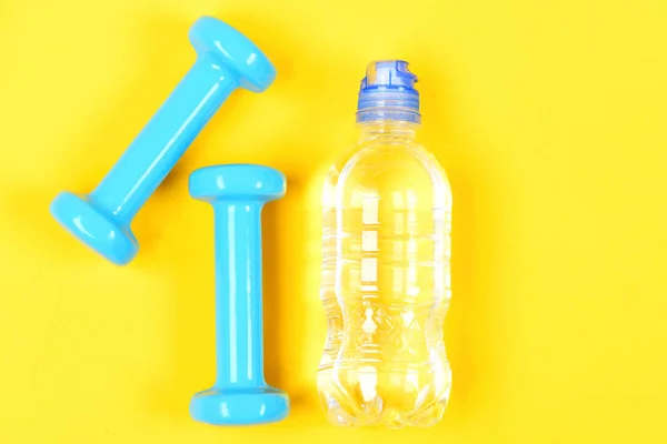 ダンベルと青黄色の背景に分離された水のボトル — ストック写真
