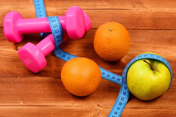 Trainingsconcept, halters gewicht met meten tape, sinaasappel en appel — Stockfoto