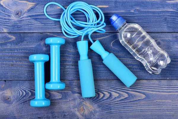 Wasserflasche, Springseil und Kurzhanteln auf blauem Jahrgang — Stockfoto