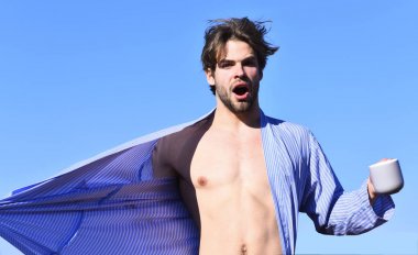 Mavi çizgili pijamalı, elinde fincanla beyaz maço.