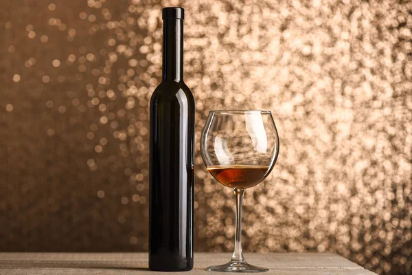Bicchiere con bevanda marrone vicino alla bottiglia di vino sulla superficie di legno — Foto Stock