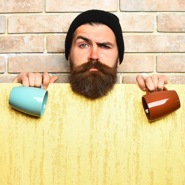 Barbudo brutal hipster caucásico con hoja de papel y tazas —  Fotos de Stock