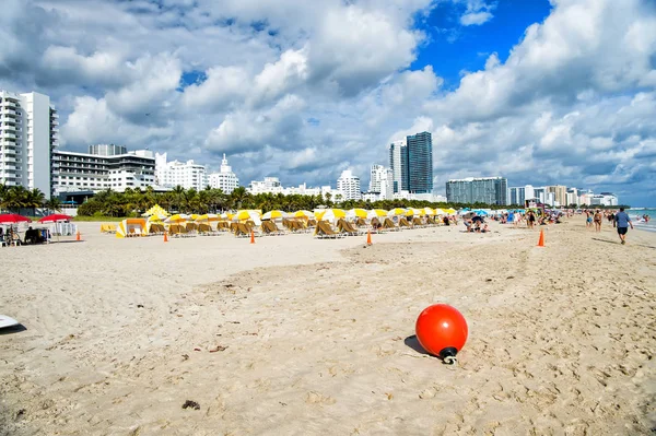 Playa de arena con tumbona bajo sombrilla amarilla — Foto de Stock